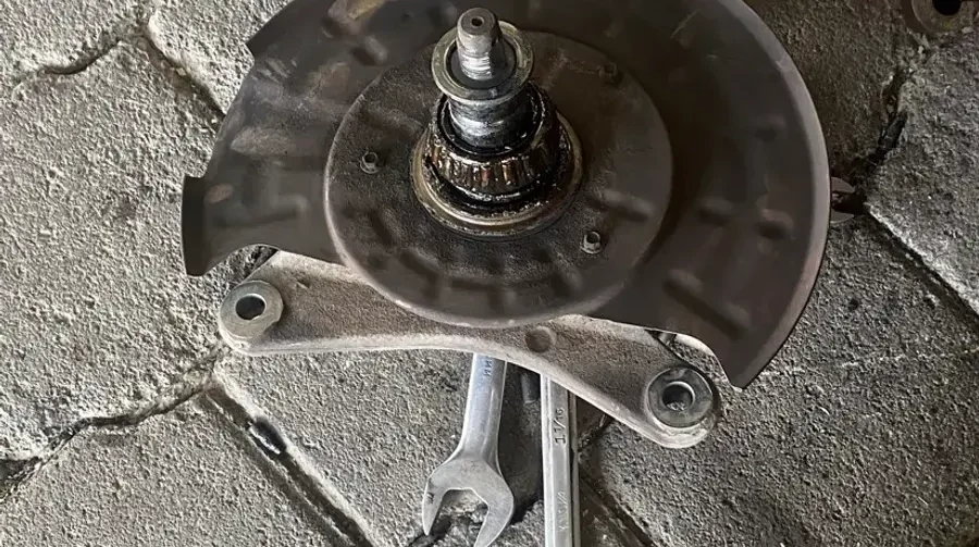 Maza y disco desmontados sobre el piso del taller junto a la llave usada